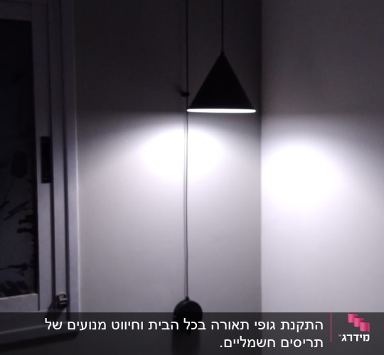 מנורה תלויה עם כבל חשמל על קיר אפור